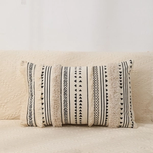 Detail of bohemian cream tufted cushion cover with black geometric patterns and tassels