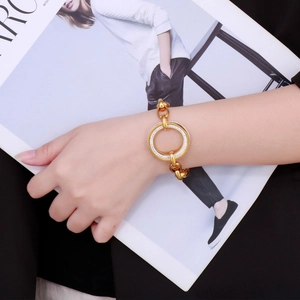 Detail of gold chain bracelet featuring a large hollow circular clasp set with rhinestones
