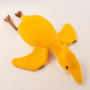 Close-up view of a soft yellow pterodactyl plush toy lying flat on a white surface