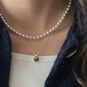 Close-up of double-layered necklace with white pearls and square leopard pendant