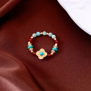 Vintage elastic ring with tiger eye agate beads and gold clover charm on silk background