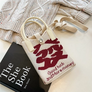 Close-up of knit phone bag featuring red character embroidery and good luck slogan