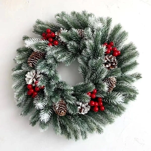 Christmas wreath with LED lights, pine cones and red berries on snow-tipped pine needles