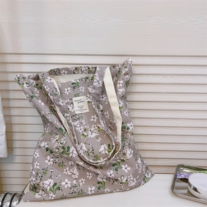 Dettaglio della borsa tote in tela floreale con motivi a piccoli fiori e manici intrecciati