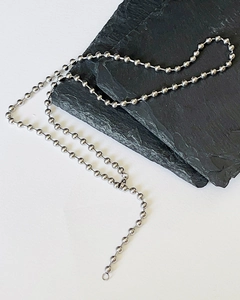 Close-up of polished silver bead necklace on natural slate with metallic mirror finish