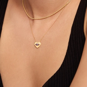 Detail of layered S925 silver necklace with golden twist chain and evil eye heart pendant
