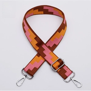 Macro shot of colorful woven shoulder strap with pink geometric patterns and silver hooks