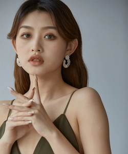 Close-up of model wearing large gold-tone stud earrings with sparkling crystals