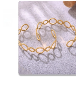 Macro shot of 18K gold plated threaded ring open bangle with artistic shadow on fabric