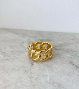 Top view of a chunky gold Cuban link chain ring displayed on a marble surface