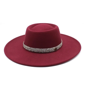 Detail of burgundy wool fedora featuring a shiny diamond band and gold M letter metal pin