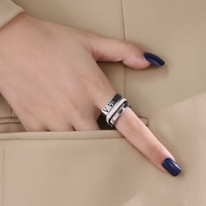 Detailed close-up of layered Roman numeral rings set in titanium steel on hand