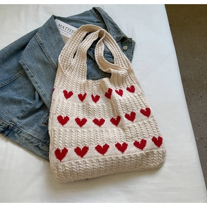 Detalle de bolso tote de punto blanco roto con corazones rojos y textura tejida
