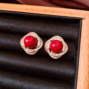 Detailed close-up of a red zircon pearl earring with gold setting on black velvet