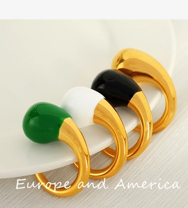 Detail showing four teardrop enamel rings in green white and black on a white ceramic plate