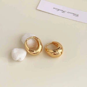 Detail view of gold water-drop earrings with mirror polish finish on white stones