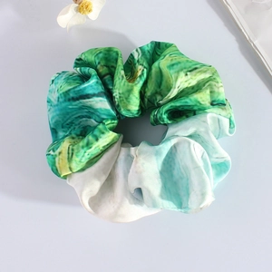 Detail of green and white oil painting marble print satin scrunchie on flat lay surface
