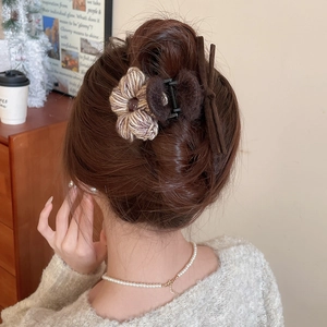 Détail de la pince à cheveux fleur en laine tricotée avec rubans portée par un mannequin