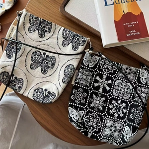 Détail de sacs bandoulière en toile vintage avec broderies de papillons et de fleurs