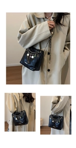 Detail of black quilted leather bucket bag with colorful charms on the dual chain straps