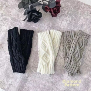 Detalle de mitones de punto tricolores con patrón de rombos sobre fondo de mármol gris