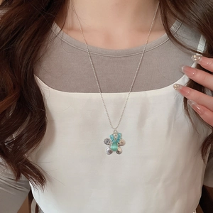 Close-up of floral cat-eye stone necklace with blue beads and silver chain on model