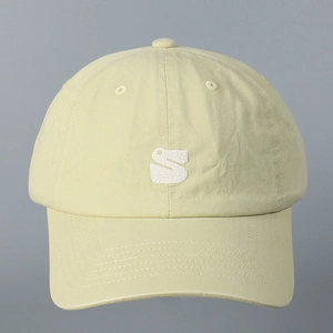 Detail of embroidered white S letter on pale yellow cotton twill baseball cap