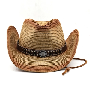 Detail of western straw cowboy hat featuring brown leather band and silver sun emblem medallion