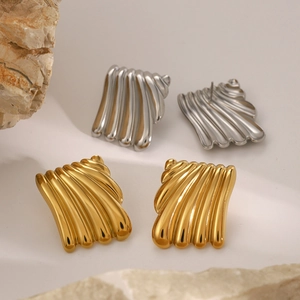 Detail view of gold and silver irregular square wave earrings on a natural stone base