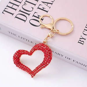 Sparkling red crystal heart keychain with golden metal clasp on a pink fashion book