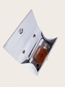 Detail view of the silver evening clutch interior with smartphone and perfume for size scale