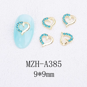 Vue macro de bijoux d'ongles en forme de cœur doré 9x9mm avec strass bleu clair