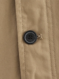 Close-up of khaki canvas jacket fabric with a black button and detailed stitching