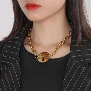 Close-up of a gold Tree of Life pendant necklace on chunky chain worn by a model