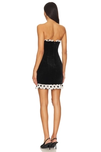 Vue arrière d'une mini robe en velours noir avec volants à pois blancs et fermeture éclair