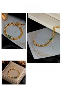 Detail of K18 stamped clasp on a gold double-layer chain bracelet with emerald gemstone
