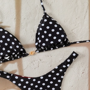 Detailed view of polka dot bikini top featuring a golden sun-shaped metal ornament