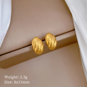 Detail of golden spiral stud earring 8x13mm weighing 2.3g on pink velvet display