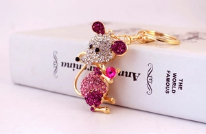 Macro detail of gold-tone mouse keychain featuring sparkling pink rhinestone inlay