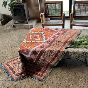 Close-up of bohemian orange woven blanket showing intricate patterns and tassel fringe edge