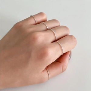 Detail of five minimalist thin silver textured rings worn on a hand set in high quality