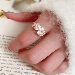 Detailed view of silver flower ring with gold core on soft white textured fabric