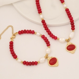 Detail view of red agate beads and baroque pearls on a vintage gold necklace and bracelet set