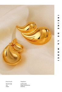 Detail of 18K gold plated water drop earrings on soft silk fabric showing high polish finish