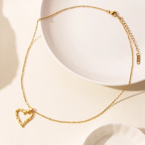 Detailed view of golden heart pendant with hammer texture on polished stainless steel