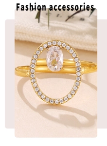 Macro detail of gold-plated geometric ring featuring a large oval cubic zirconia stone