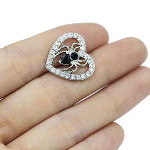 Close-up of heart-shaped spider belly button ring with silver base and black zircon