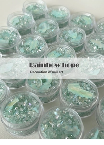 Detailed view of mint green nail art charms including crushed stones and faux pearls