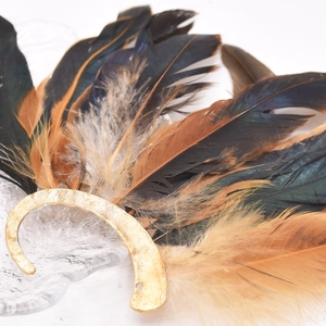 Macro detail of natural peacock feather texture and golden hand-hammered metal base