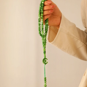 Close-up of Islamic 99 prayer beads in green with transparent star and moon pendant